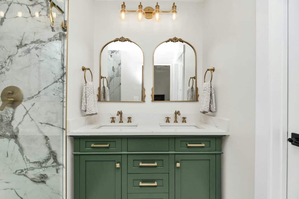 Bathroom remodel with a green vanity and marble shower wall