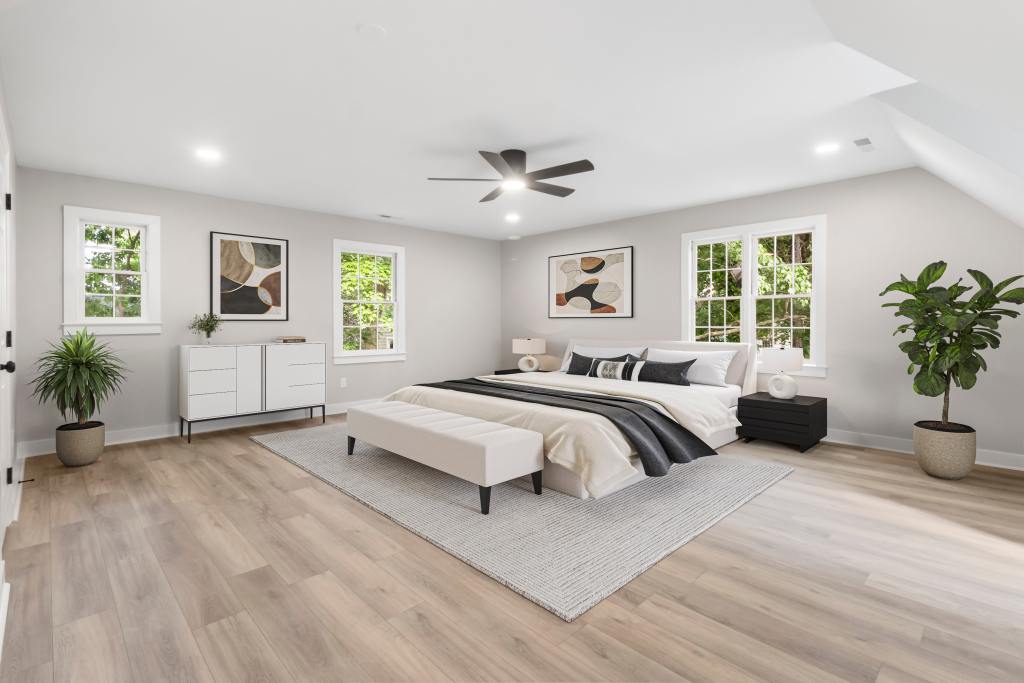 Renovated primary bedroom with a sloped dormer ceiling and light wood flooring