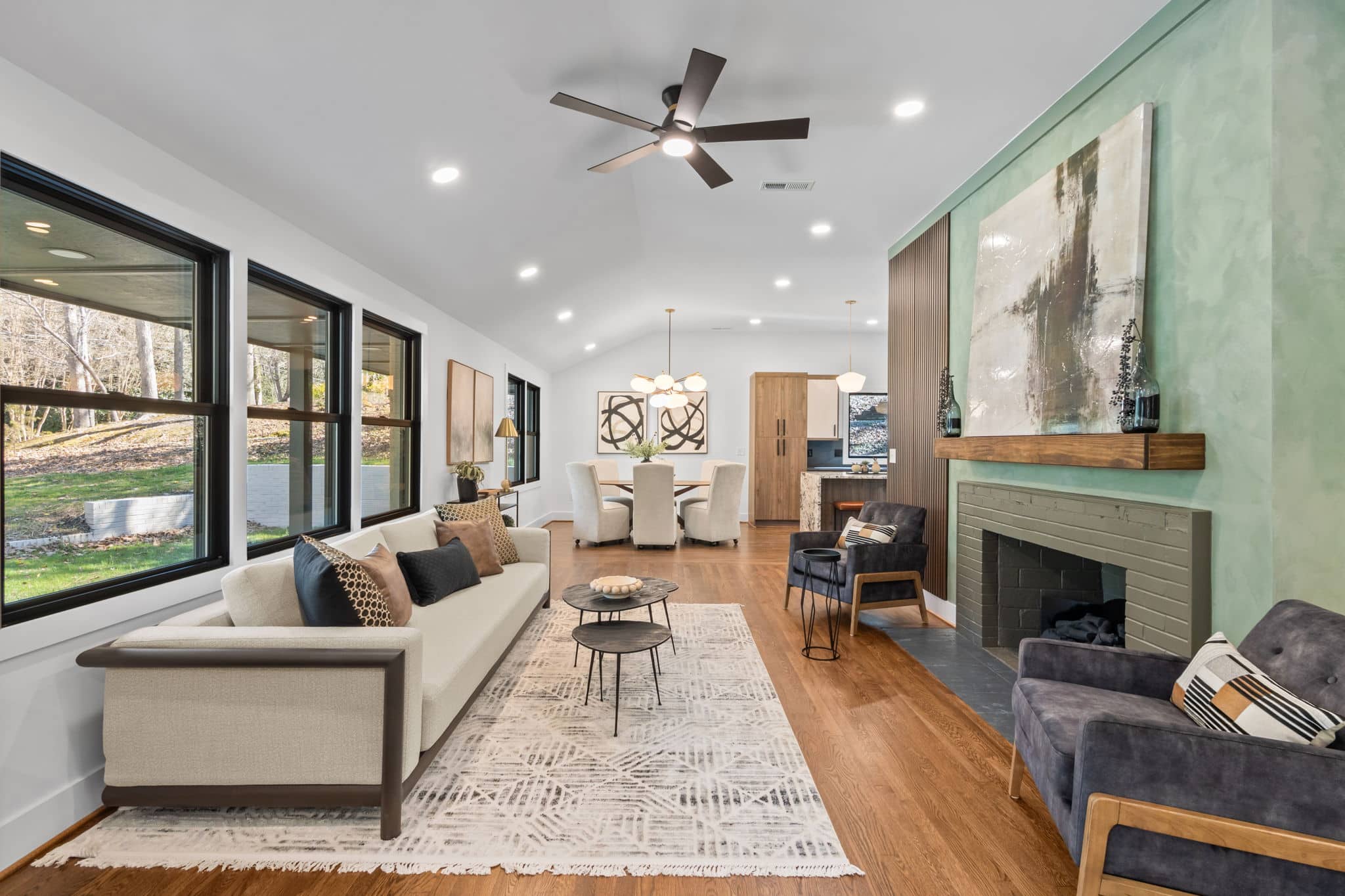Renovated open-plan living and dining room with a green plaster fireplace wall and vaulted ceiling