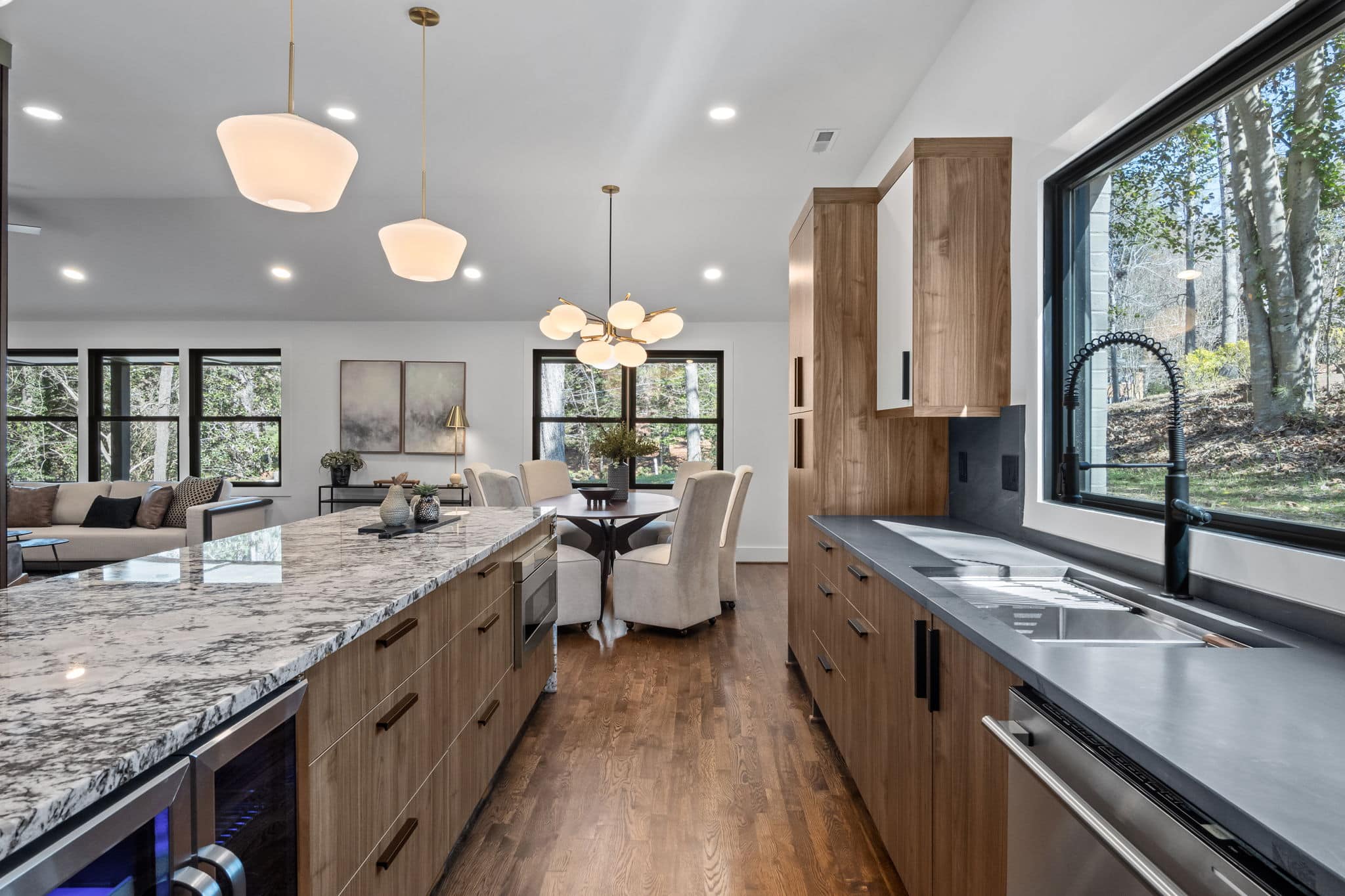 Open-plan kitchen with walnut cabinetry, a granite island and a dining table beyond